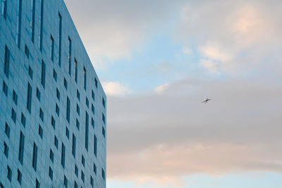 Low angle view of modern building against cloudy sky