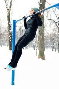 Woman doing chin-ups over snow covered field