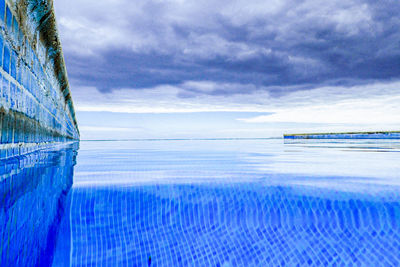 Swimming pool by sea against sky