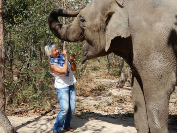 Smiling woman feeding elephant