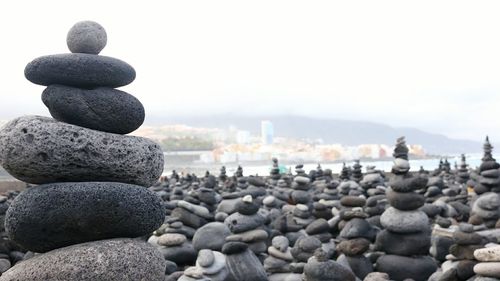 Stack of pebbles on shore against sky