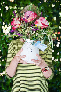 Midsection of woman holding pink flowers