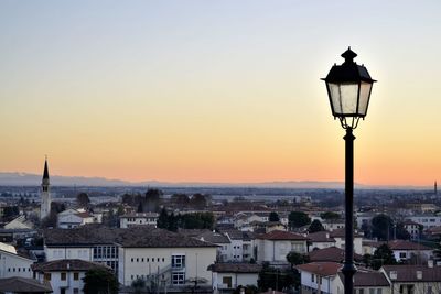 Street light and buildings in town against sky during sunset