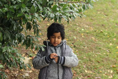 Boy standing against tree