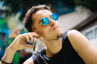 Portrait of young man holding sunglasses