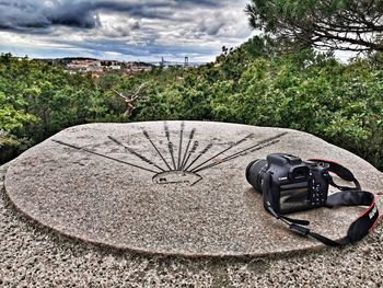 Close-up of camera on field against trees