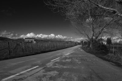 Road amidst bare trees against sky