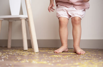 Toddler girl standing on messy floor after playing with grain, pasta rice.sensoric early development