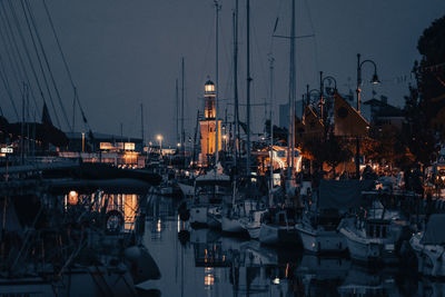 Sailboats moored at harbor against sky at night