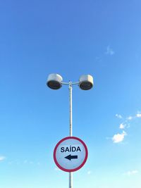 Low angle view of road sign against blue sky