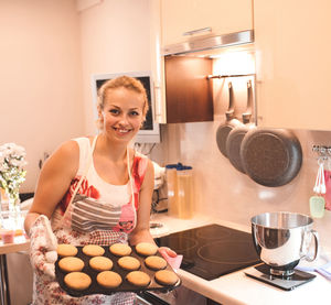 Woman with baking tray standing in kitchen