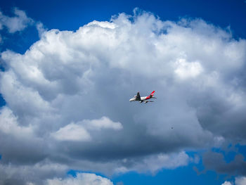 Low angle view of airplane against cloudy sky