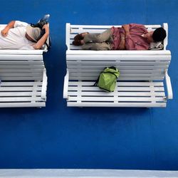 Men relaxing on bench at airport departure area