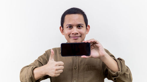 Portrait of smiling man photographing against white background