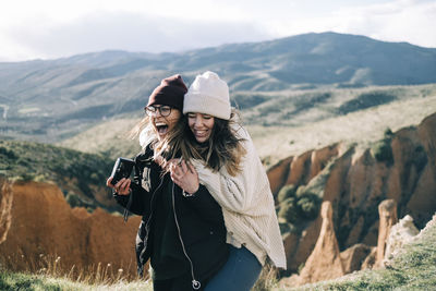 Young woman photographing with umbrella standing on mountain