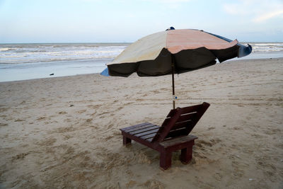 Deck chairs on beach against sky