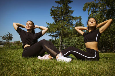 Girl in sportswear on a sunny summer day on the embankment in the park doing fitness and stretching