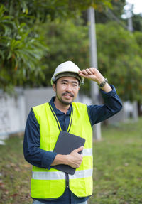 Portrait of young man standing against trees