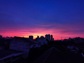 Silhouette buildings against sky at sunset