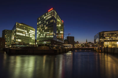 Illuminated buildings against clear sky at night