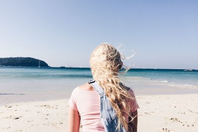 Rear view of woman on beach against clear sky