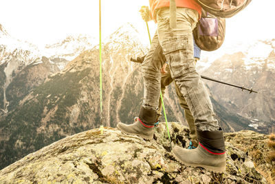 Low section of man standing on mountain against sky