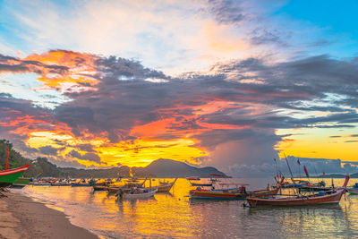 Boats moored in sea against sky during sunset