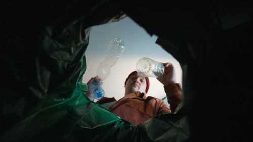 Man throwing a plastic bottle into a trash bin. bottom view from the trash bin. eco concept 