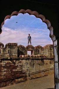 Low angle view of man standing at fort against sky