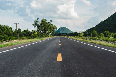 Empty road amidst trees against sky