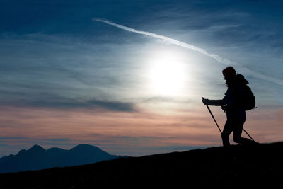 Silhouette man standing on mountain against sky during sunset