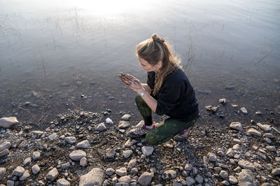 Woman putting mud on hands and face while enjoying outdoors in nature.