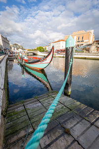 Boats moored in river by city against sky