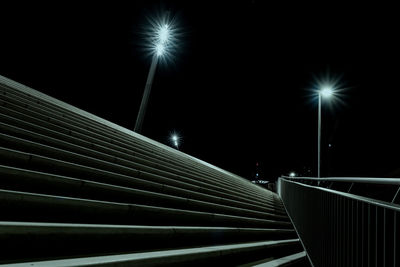 Illuminated street lights against sky at night