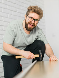 Portrait of young man using mobile phone while sitting on table