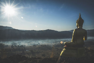 Statue of buddha against mountain and sky