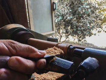 Cropped hand of man carving wood in workshop