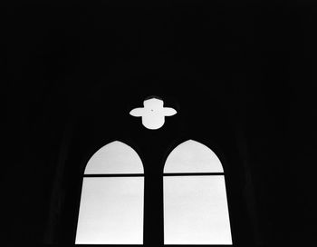 Low angle view of silhouette cross on building against sky at night