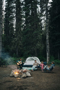 A group of friends sit around a campfire while camping in oregon.