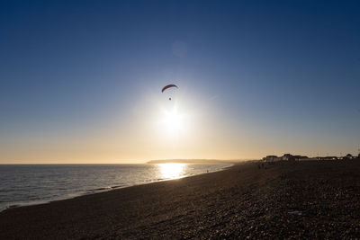 Scenic view of sea against sky during sunset with paraglider 