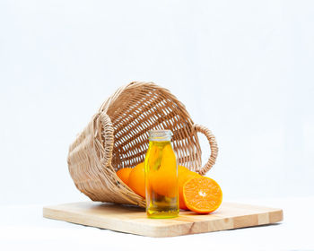 Close-up of oranges in glass jar on table against white background