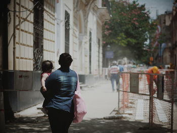 Rear view of people walking on street against buildings