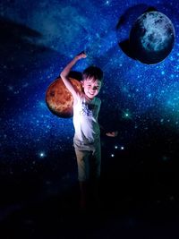 Digital composite image of boy standing against blue sky at night