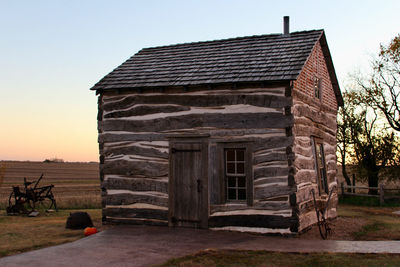 Exterior of old house on field against sky during sunset