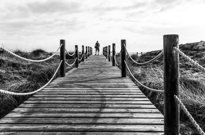 Wooden footbridge against sky