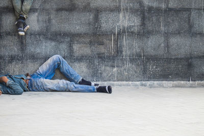 Low section of man sitting on floor against wall