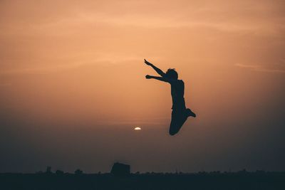 Silhouette man jumping against sky during sunset