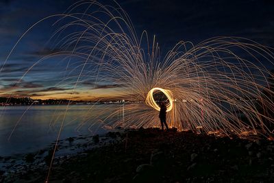 Person spinning wire wool on beach at night