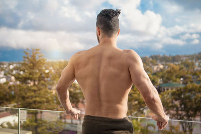 Rear view of shirtless man standing against sky