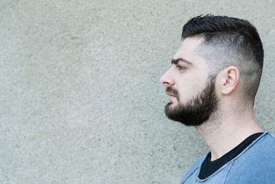 Side view of man looking away against wall